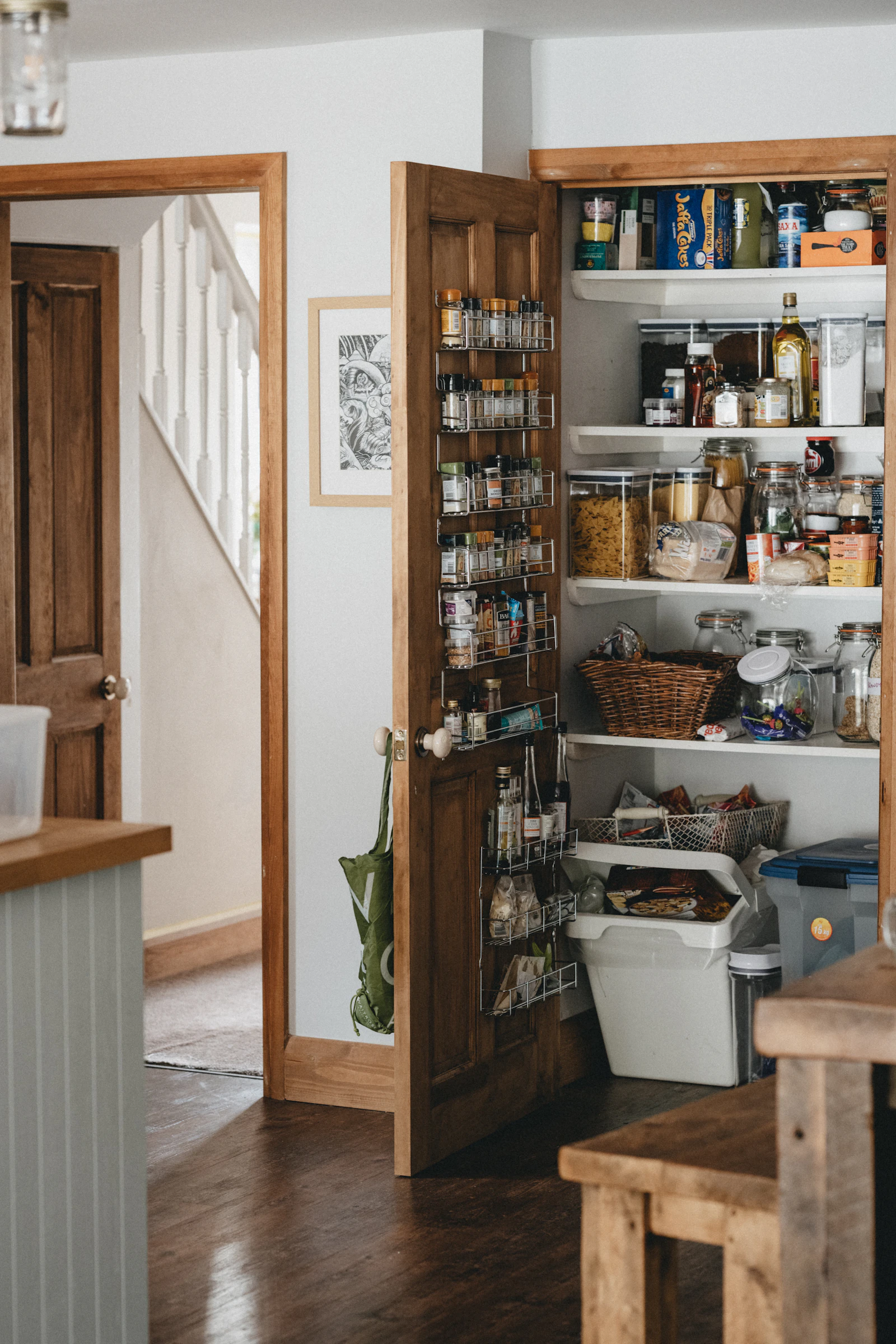 A wooden pantry shelf lined with bottles and jars