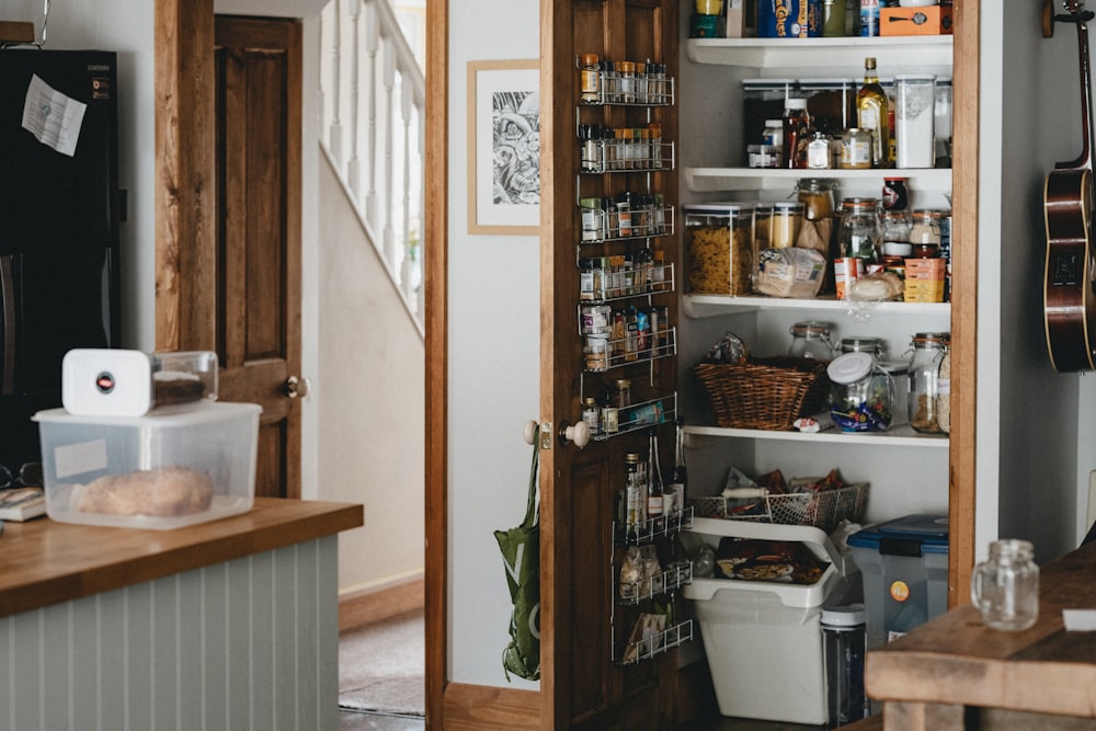 white plastic trash bin beside brown wooden shelf