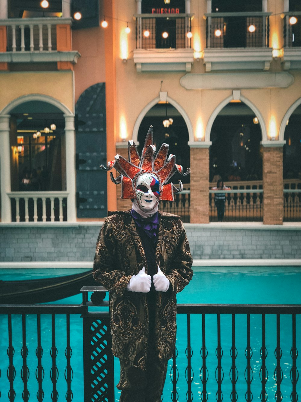 a man wearing a mask and costume standing in front of a pool