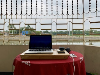 A sleek audio-video phone setup on a rustic wooden table with the red desert landscape in the background.