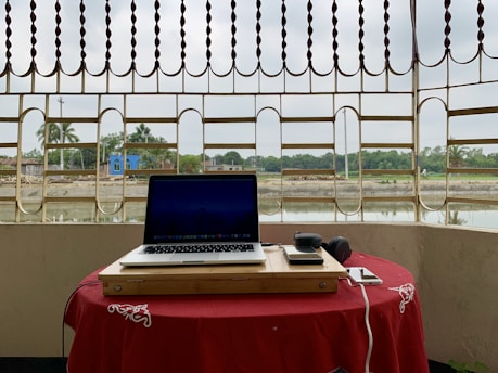A sleek audio-video phone setup on a rustic wooden table with the red desert landscape in the background.