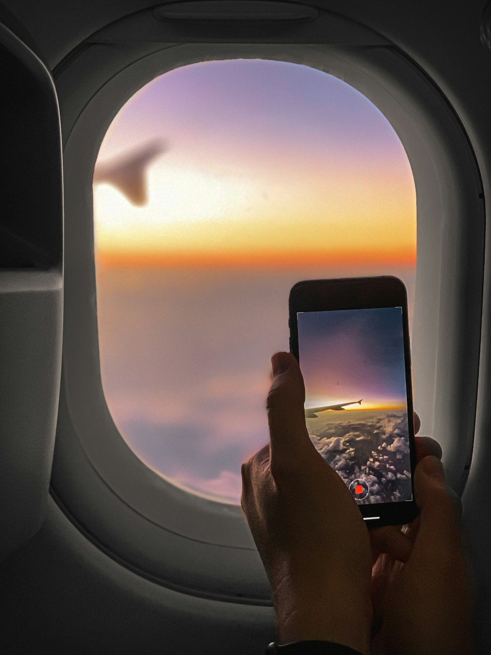 a person holding a cell phone in front of an airplane window