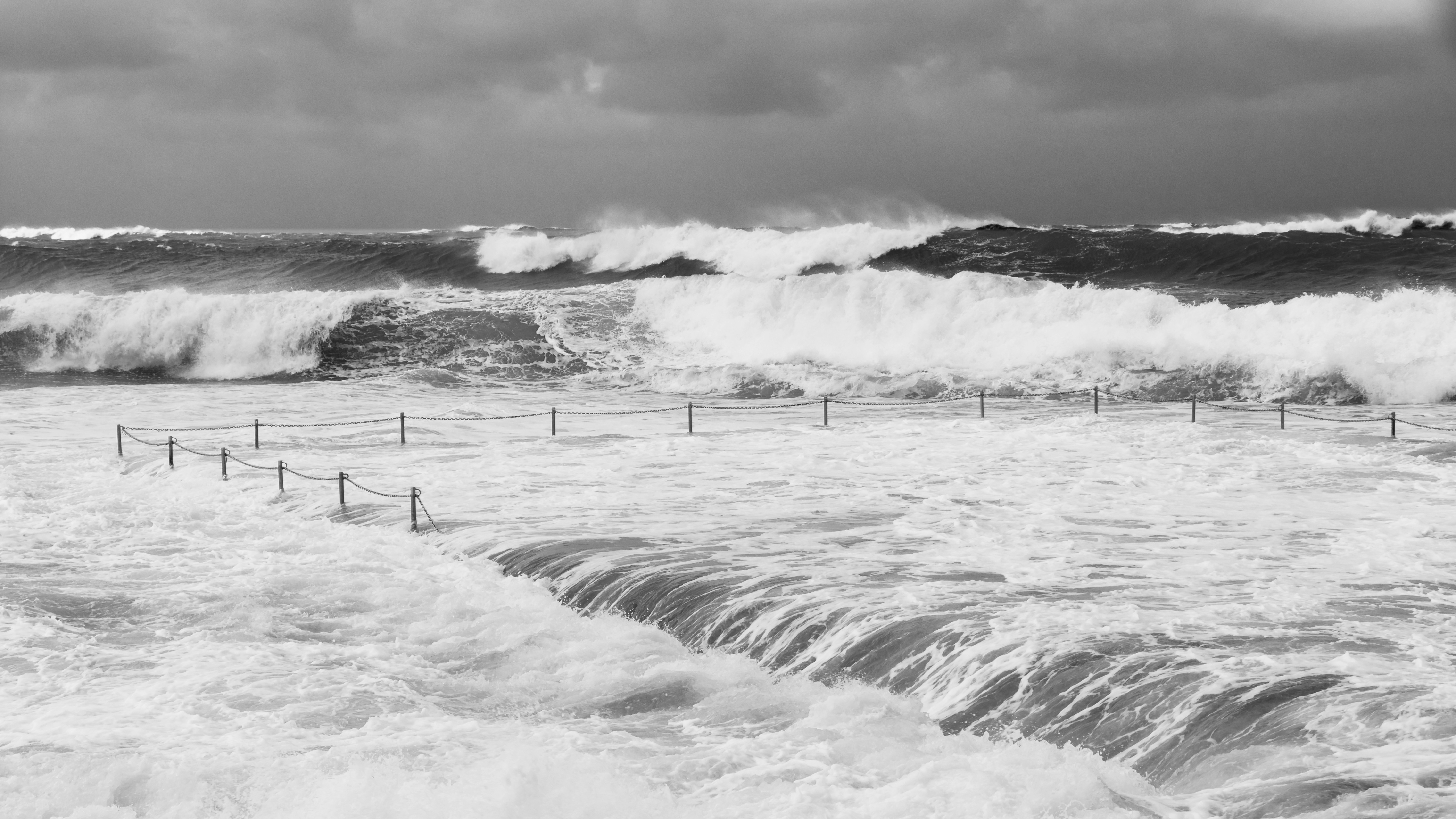 foto em tons de cinza de ondas do mar batendo na costa