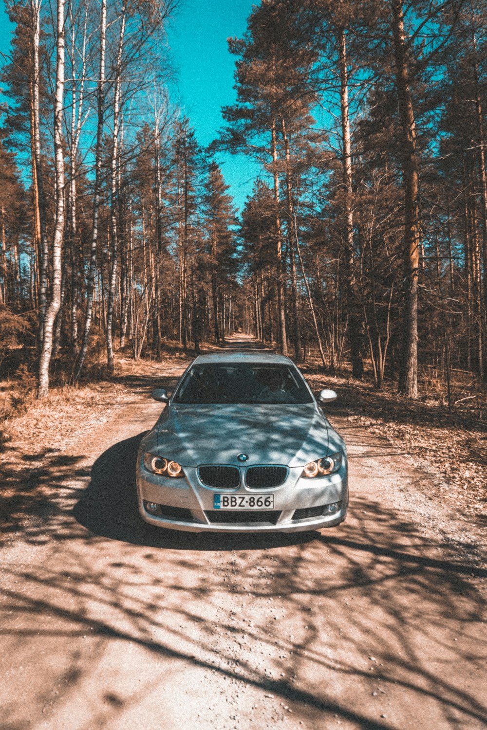 black bmw m 3 parked on brown dirt road in between trees during daytime