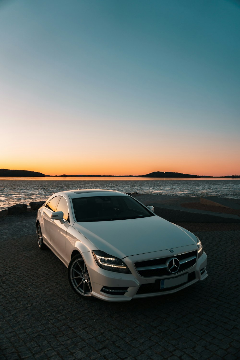 Mercedes Benz Clase C blanco en la playa durante la puesta de sol