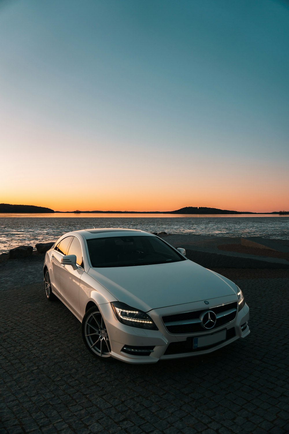 Weiße Mercedes Benz C-Klasse am Strand bei Sonnenuntergang