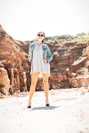 A stylish woman wearing a fitted denim jacket paired with a flowing floral dress, standing confidently outdoors.