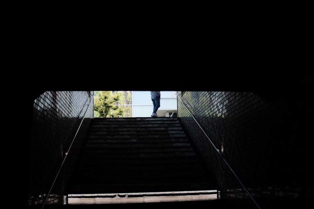 man in blue shirt standing on brown wooden stairs