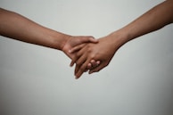 Close-up of hands gently holding each other in support during a group meeting.