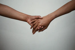 Delicate linear drawing of two hands clasped together symbolizing support.