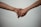 Two hands are gently holding each other against a plain background, suggesting a connection or support between the individuals.