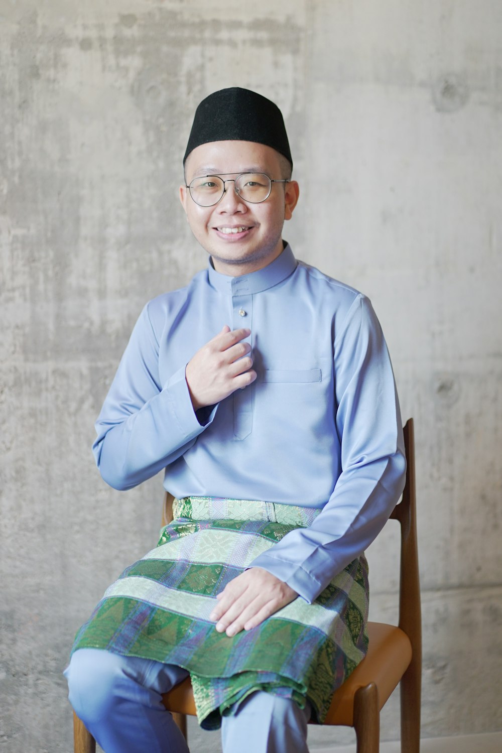 man in blue dress shirt and green and white plaid skirt