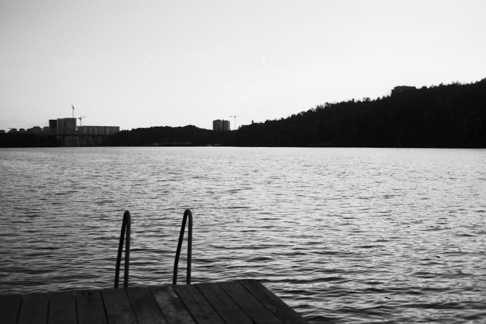 grayscale photo of wooden dock on body of water