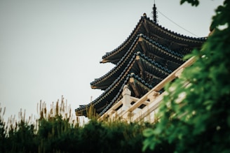 Traditional Khmer pagoda surrounded by lush greenery under soft pastel skies.