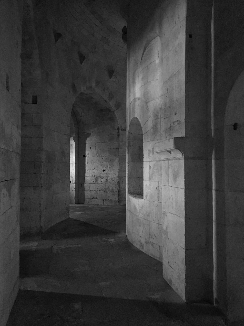 grayscale photo of concrete hallway