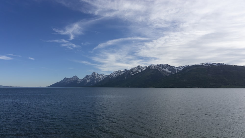 body of water near mountain under blue sky during daytime