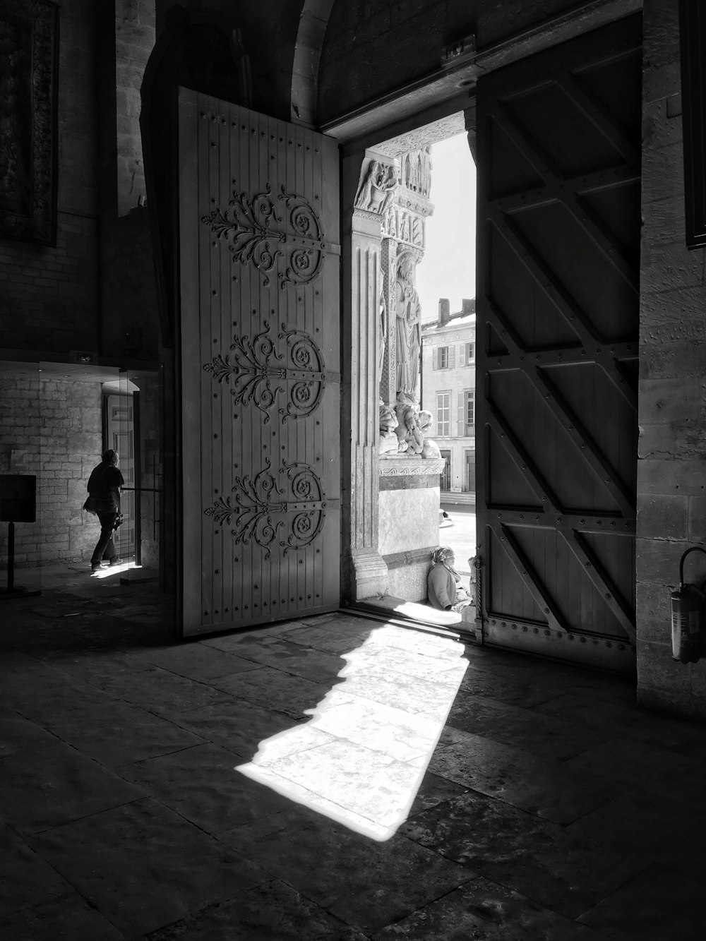 grayscale photo of man in black jacket walking on hallway