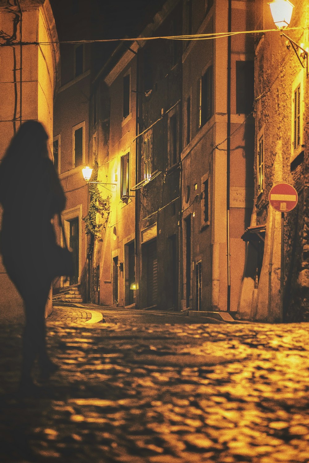 silhouette of woman walking on street during night time