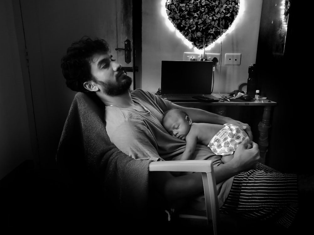 man and woman sitting on sofa in grayscale photography