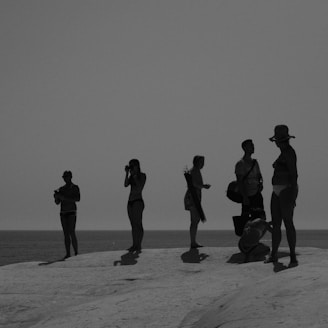 silhouette of people standing on white sand during daytime