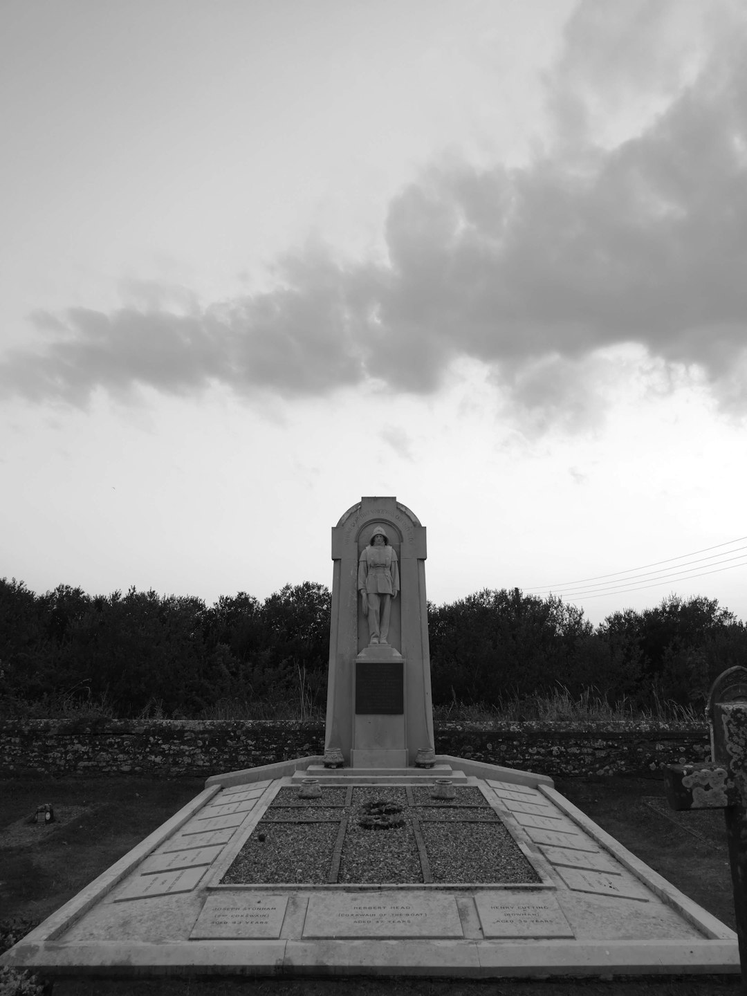 grayscale photo of concrete cross on grass field