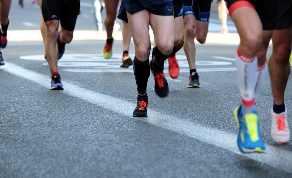 Personas corriendo por una carretera de asfalto gris durante el día