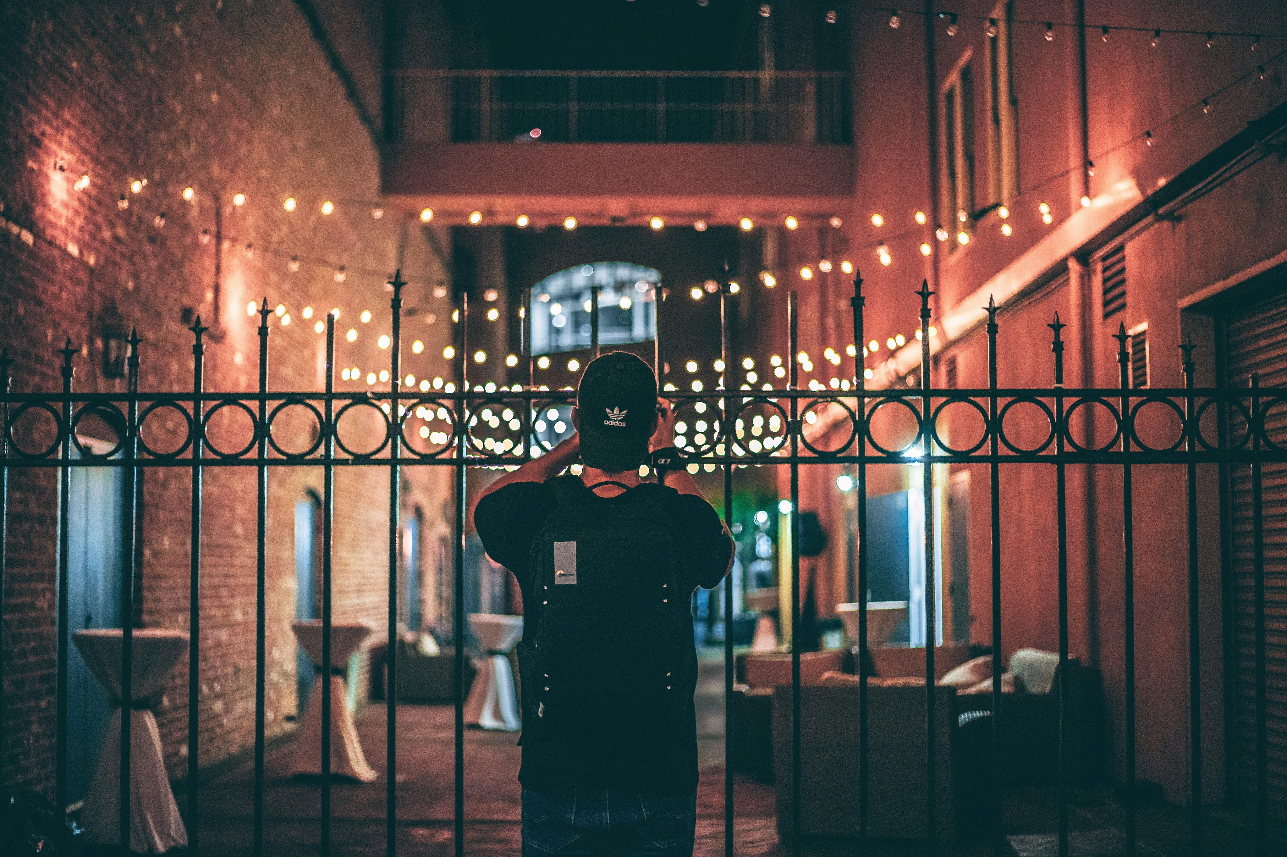 man in black crew neck t-shirt standing near brown wooden chair