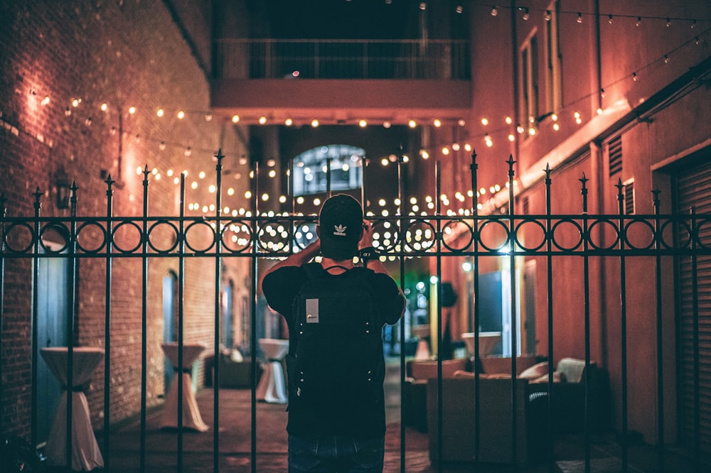 man in black crew neck t-shirt standing near brown wooden chair