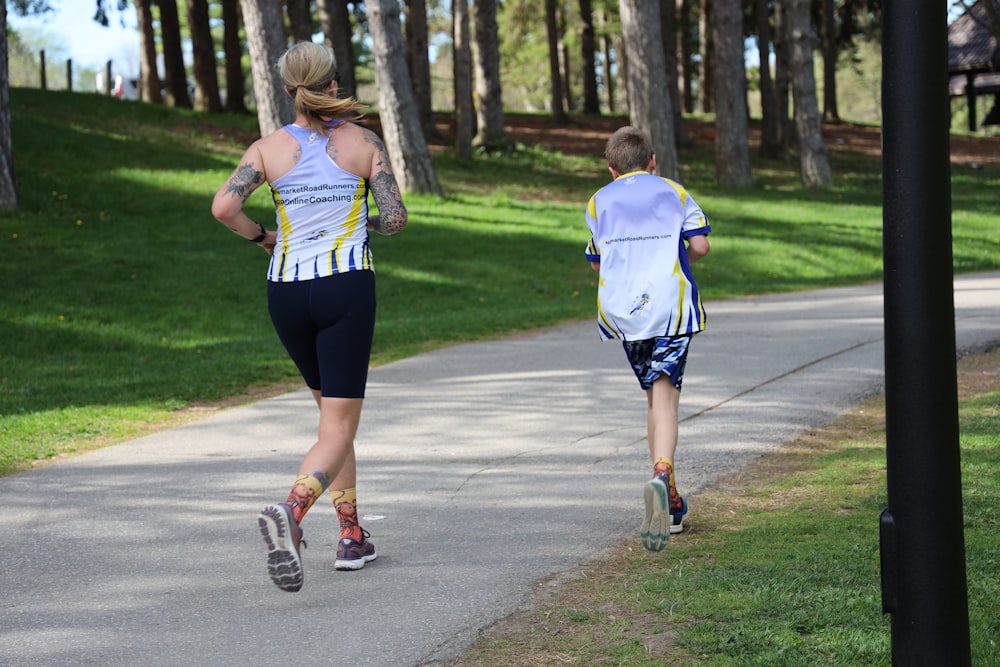 woman in blue long sleeve shirt running on gray asphalt road during daytime