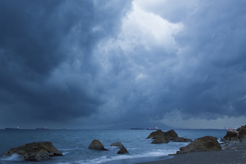 brown rock formation on sea under white clouds and blue sky during daytime