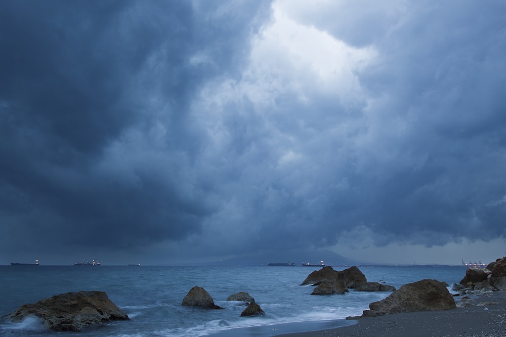 Formation rocheuse brune sur la mer sous les nuages blancs et le ciel bleu pendant la journée