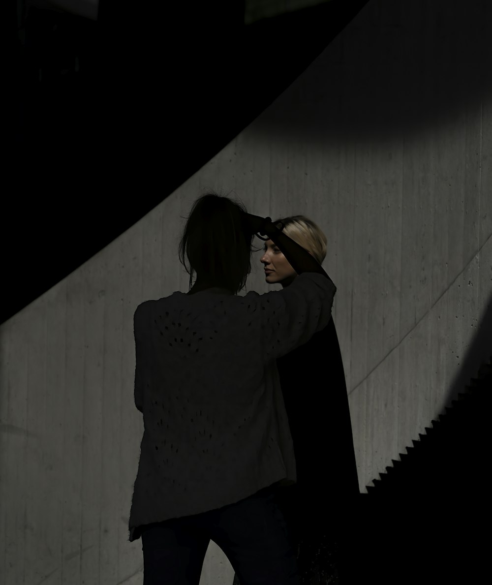 woman in black long sleeve shirt standing in front of white wall