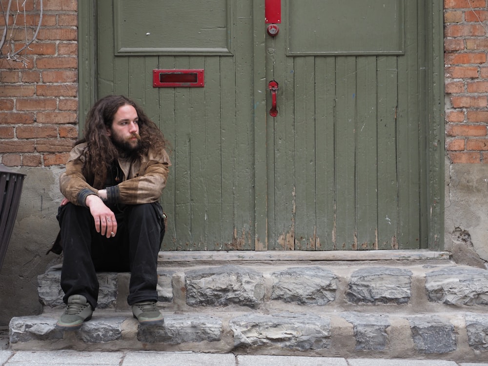 woman in brown fur coat and blue denim jeans sitting on gray concrete floor