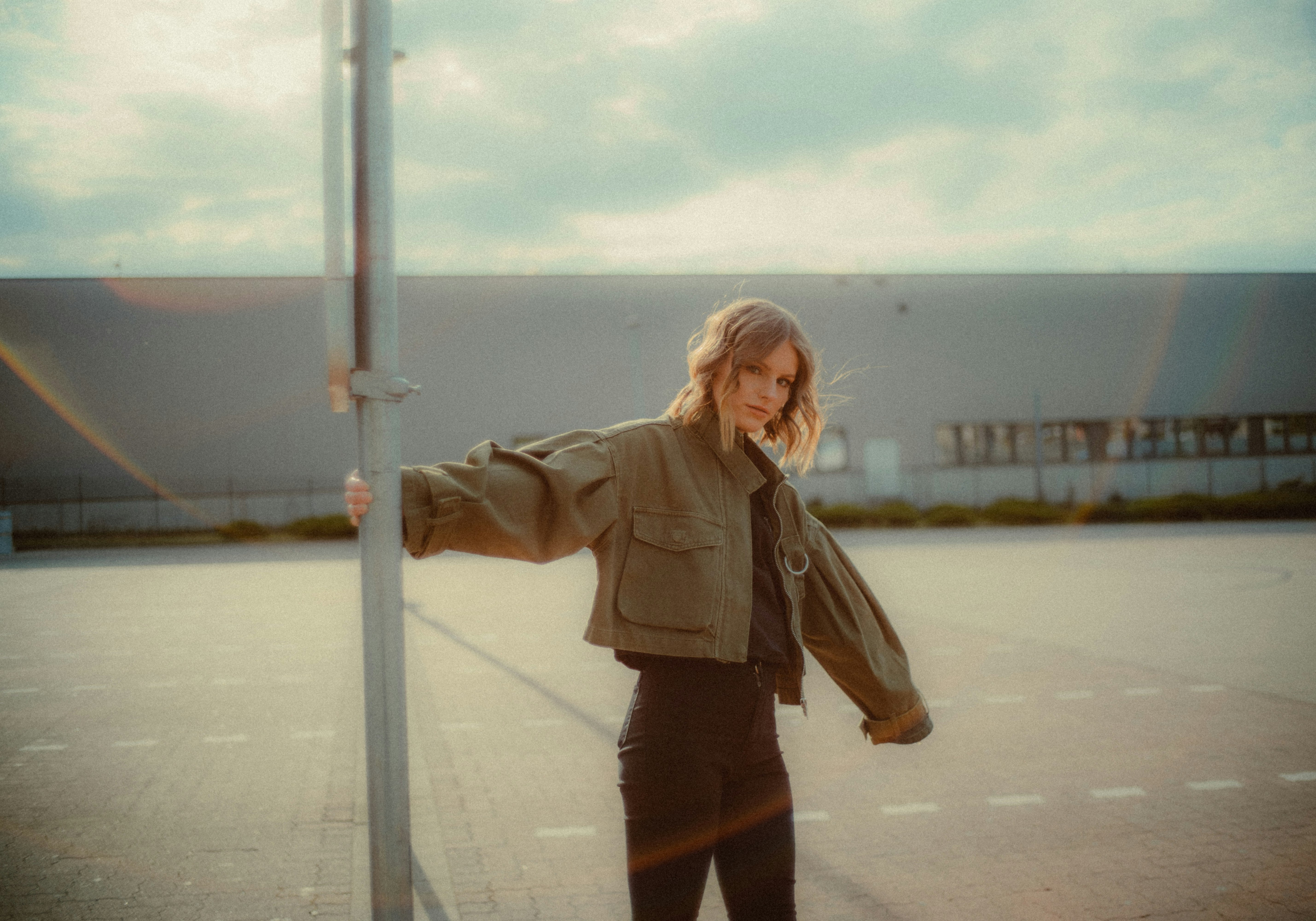 woman in brown jacket standing on gray concrete road during daytime