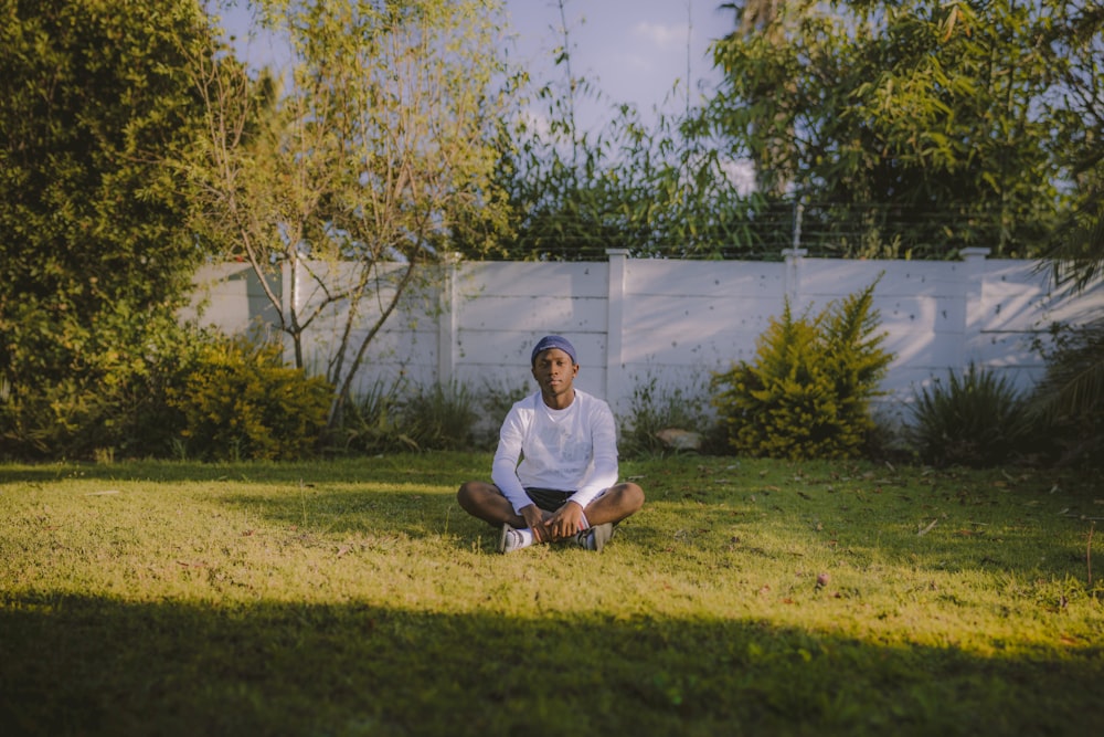 man in white crew neck t-shirt sitting on green grass field during daytime