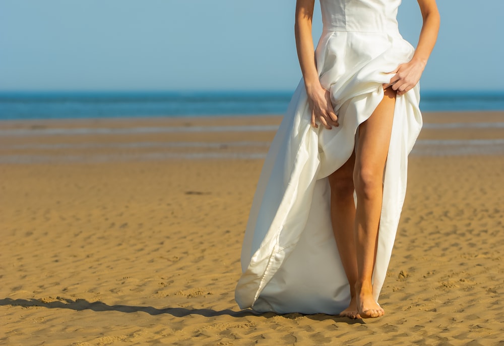 woman in white dress walking on beach during daytime