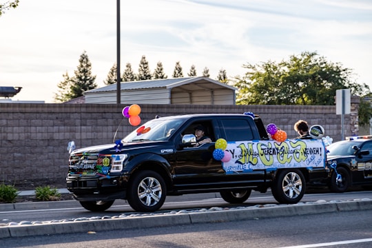A happy winner holding keys next to a shiny new GMC truck with confetti falling.