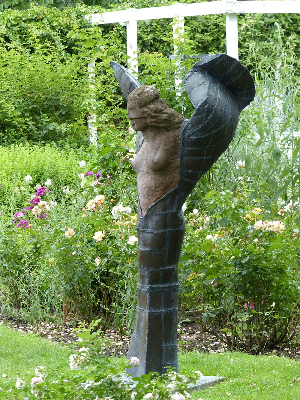 brown wooden statue near green plants during daytime