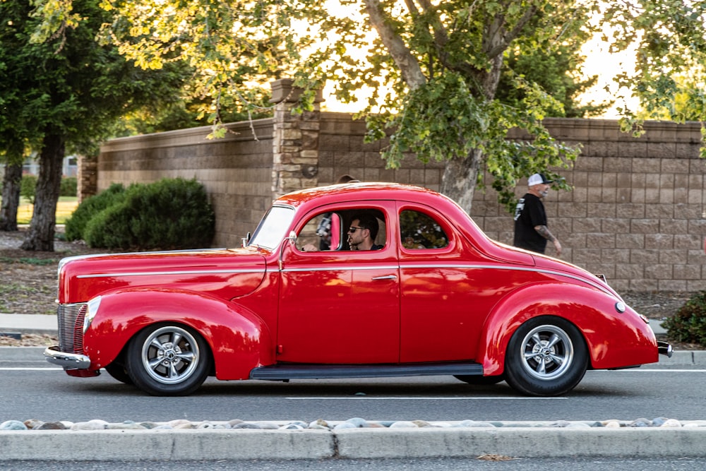 red classic car parked near people walking on sidewalk during daytime