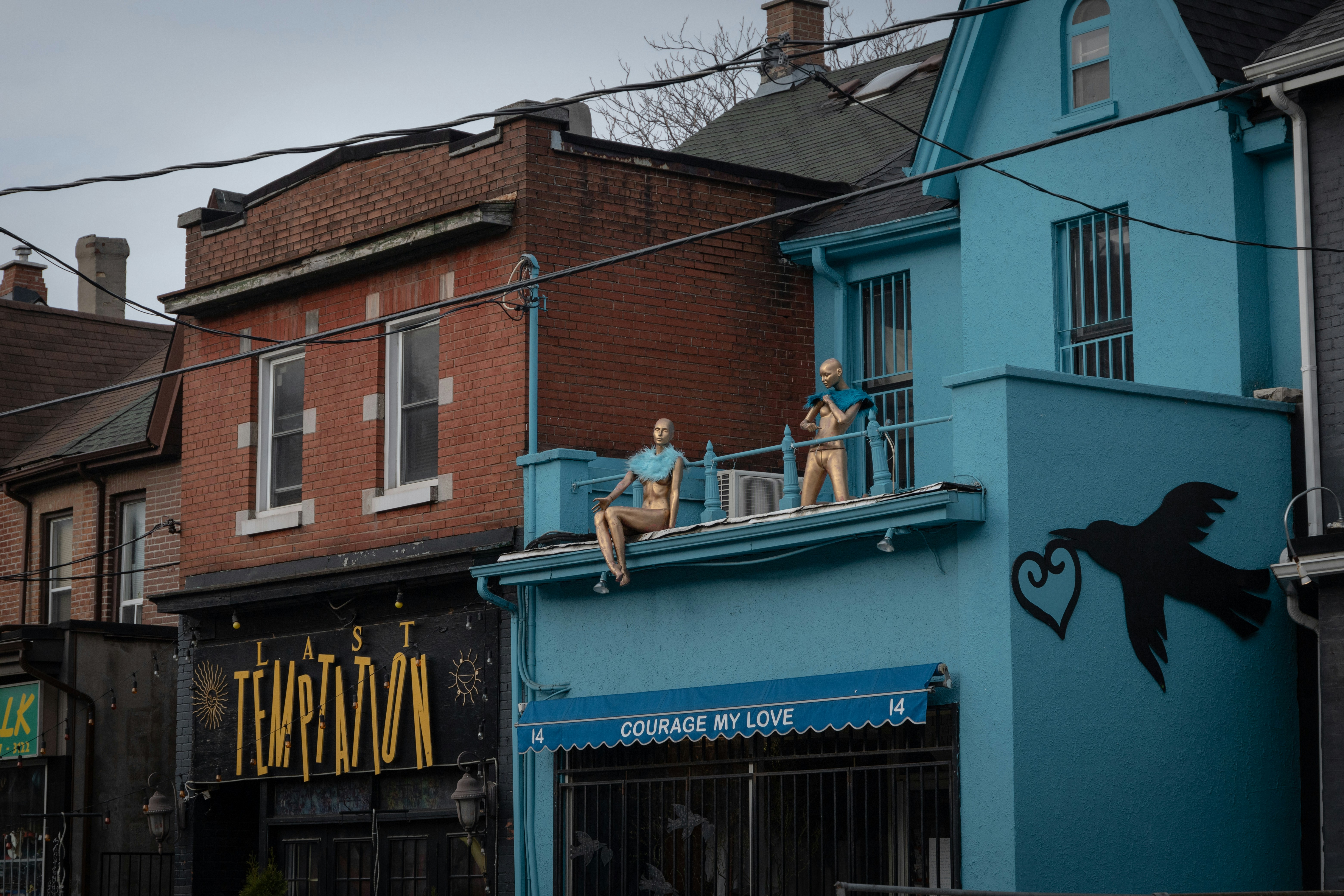 man in white t-shirt and black pants sitting on blue concrete building during daytime