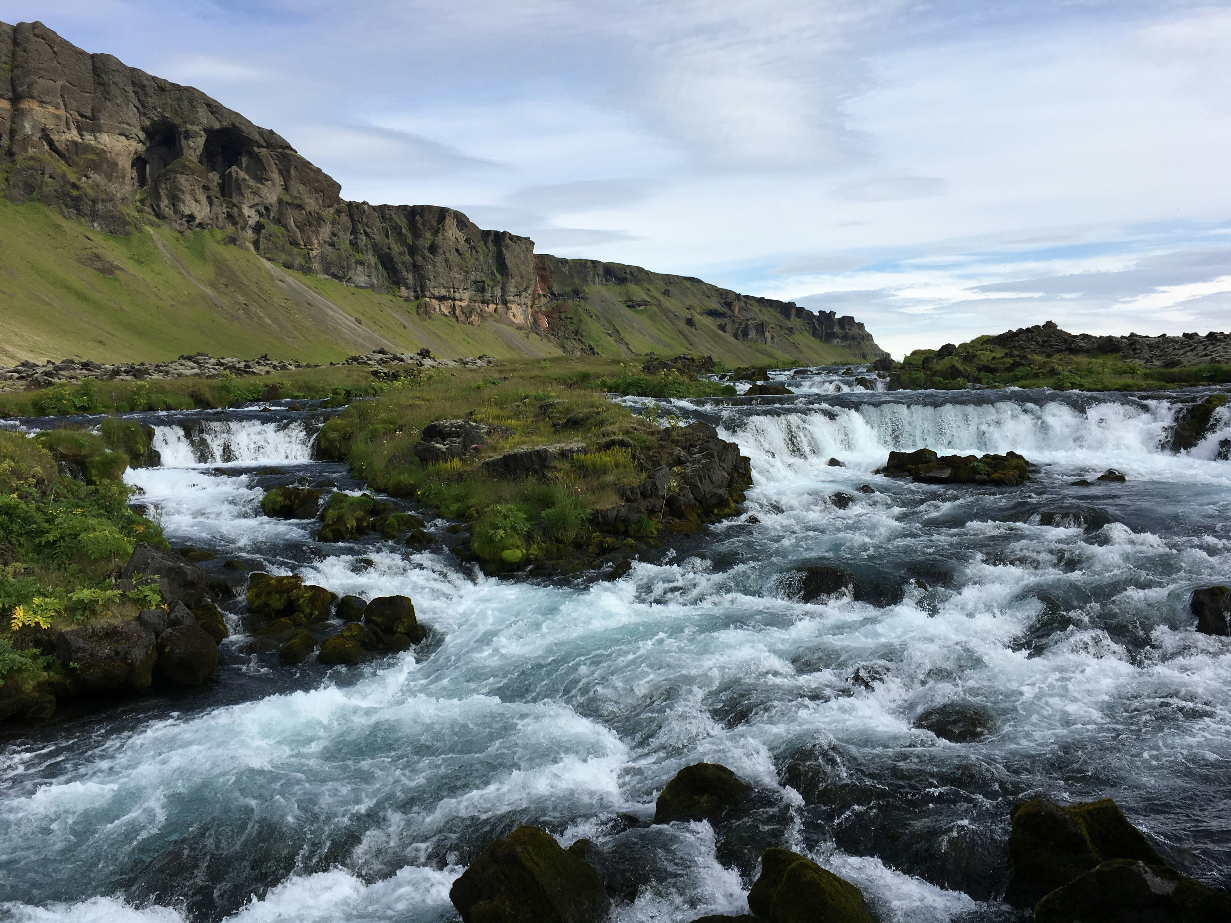 green and brown mountain beside body of water during daytime