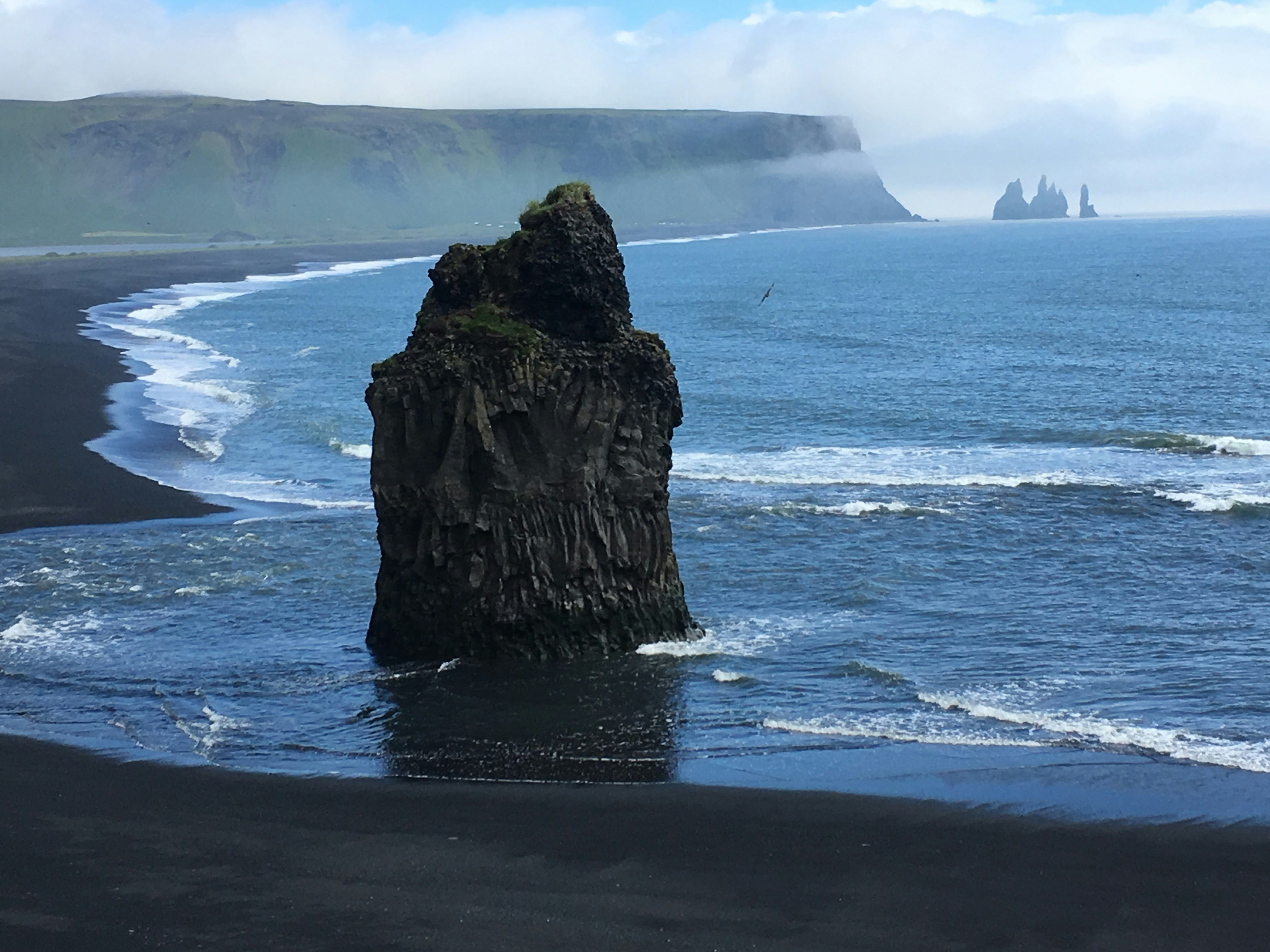black rock formation on sea during daytime