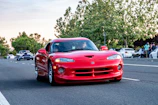 A bright red sports car gleaming under daylight on an open road.