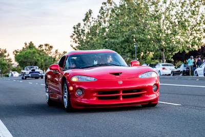 A bright red sports car gleaming under daylight on an open road.