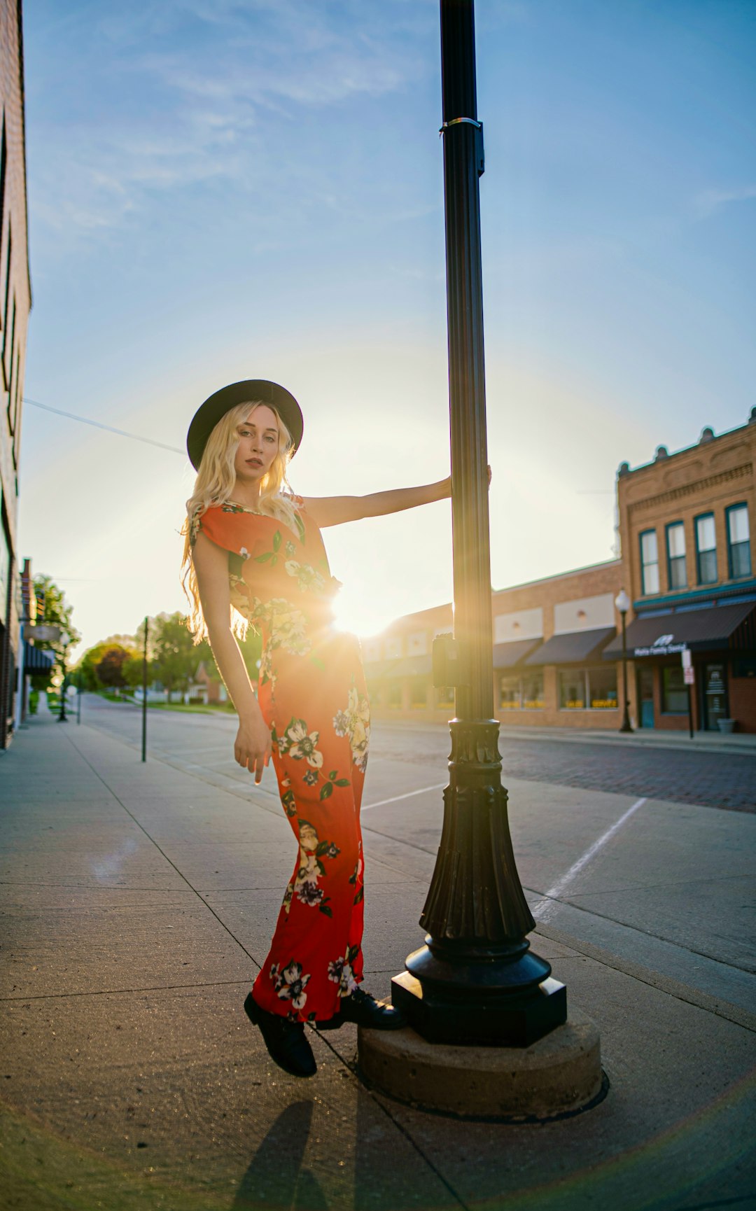 woman in white and red floral dress standing on sidewalk during daytime