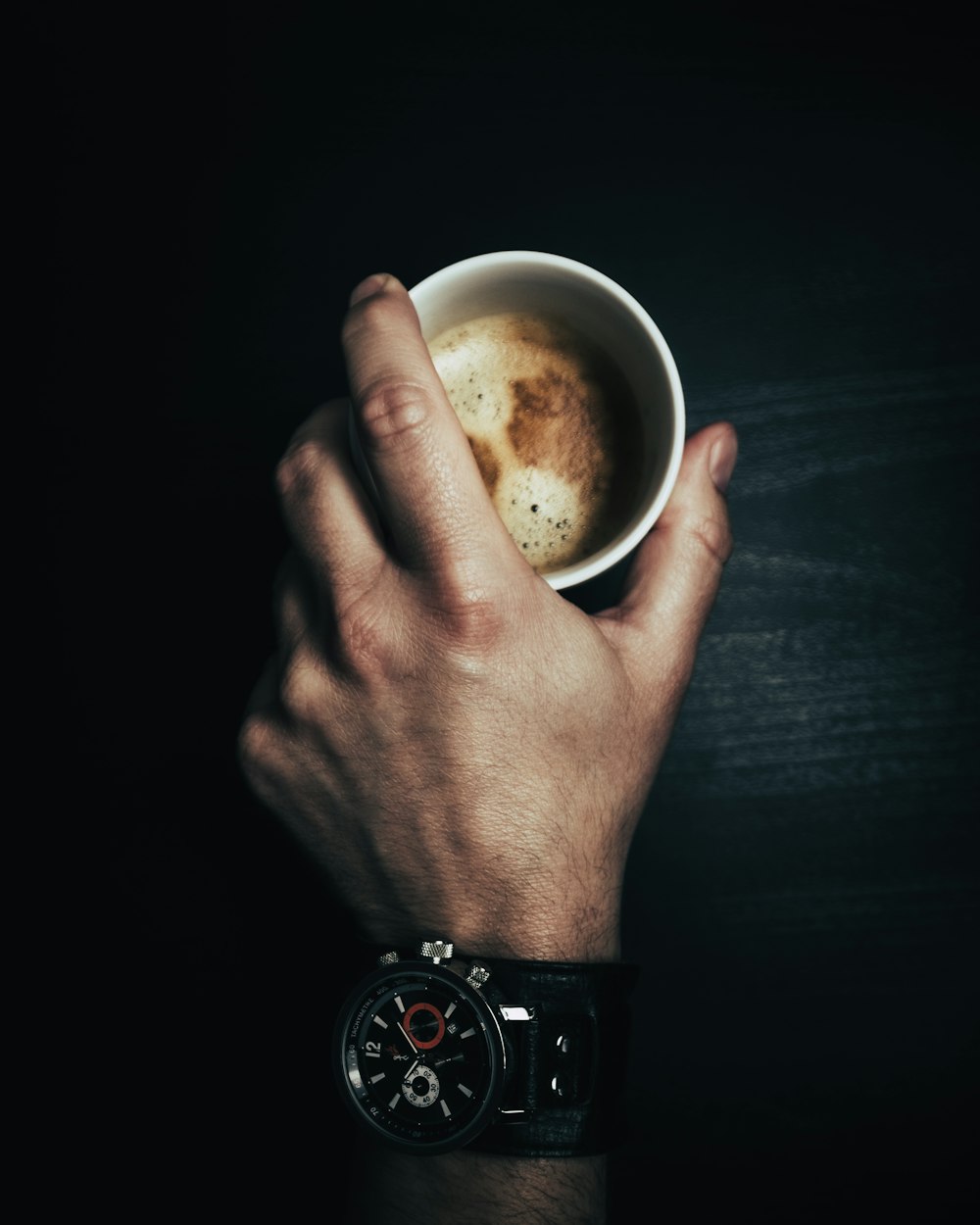 person holding white ceramic mug with brown liquid