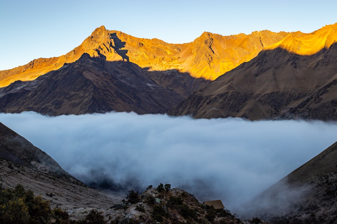 brown and black mountains under white clouds, A beautiful moody sunrise in the mountains above the clouds in Peru - by J