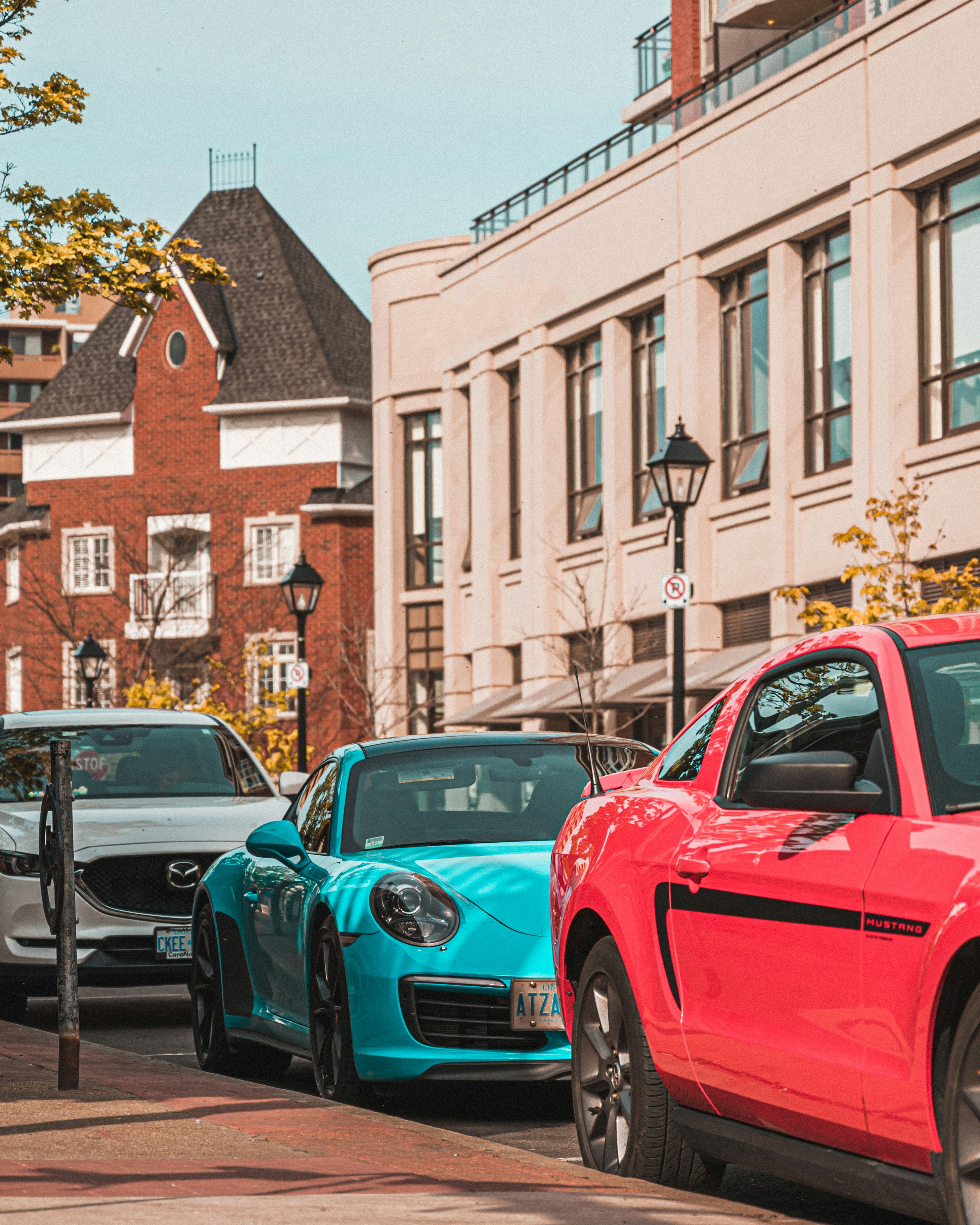 Red and blue cars parked on sidewalk during daytime photo Free Sports