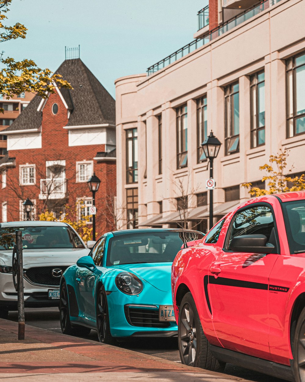 red and blue cars parked on sidewalk during daytime