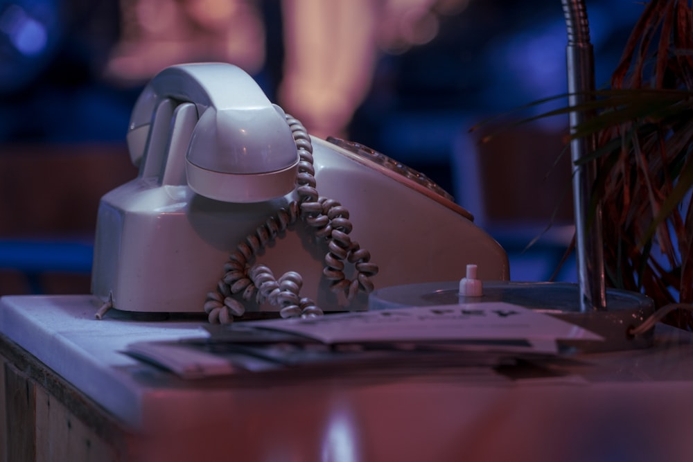 white and black corded telephone on white textile